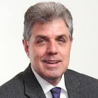 A man and a woman are sitting on a dock overlooking a lake.