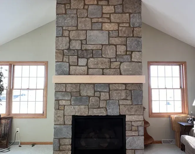 A stone fireplace in a living room with a vaulted ceiling
