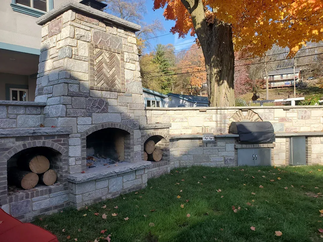 There is a fireplace in the backyard with logs in it.