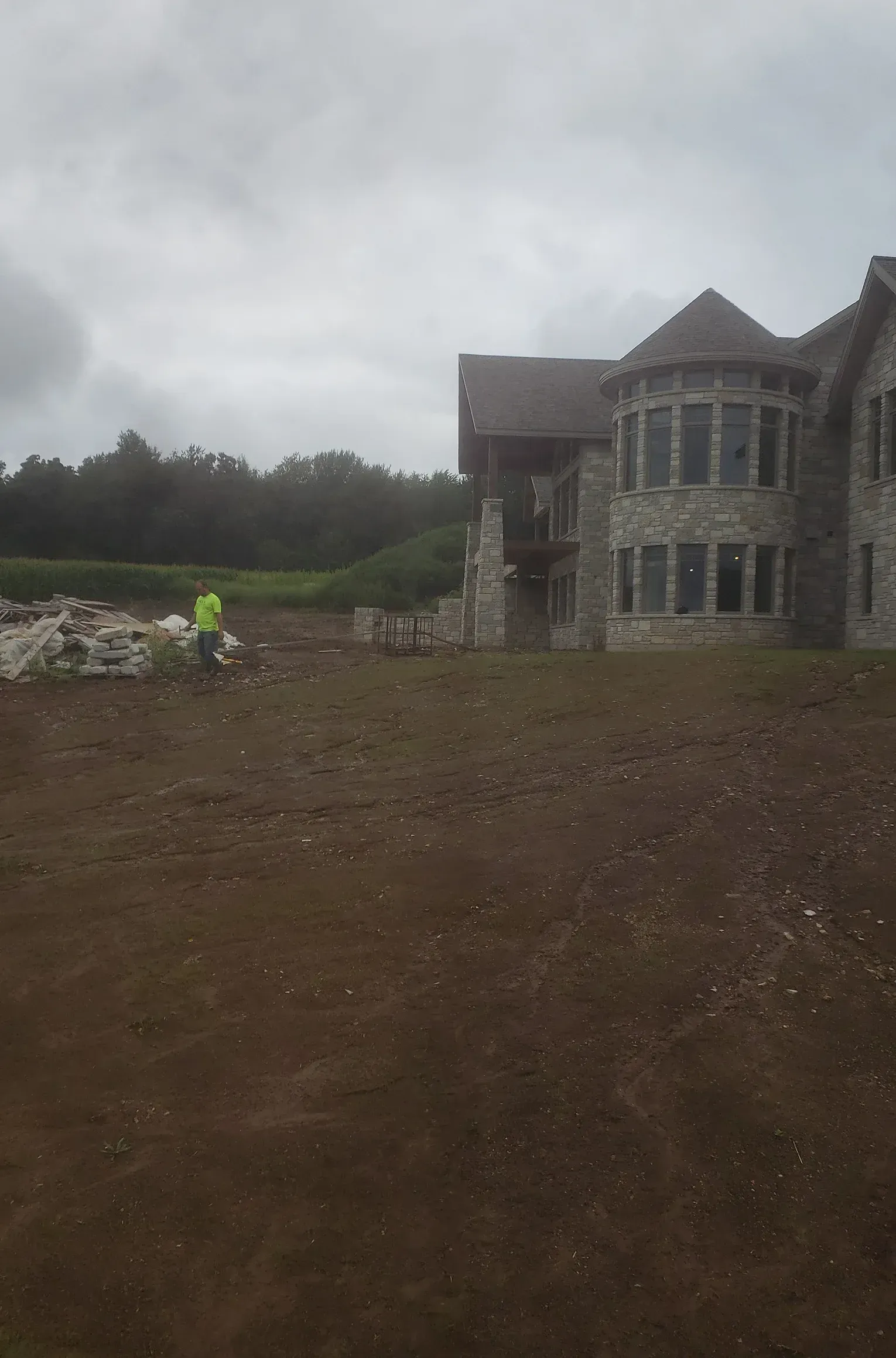 A large stone house is being built in the middle of a dirt field.