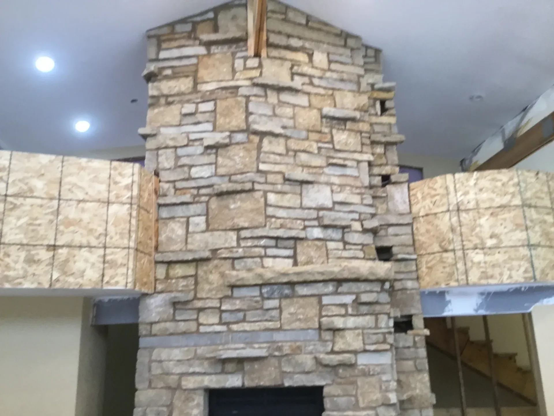 A large stone fireplace with a staircase in the background