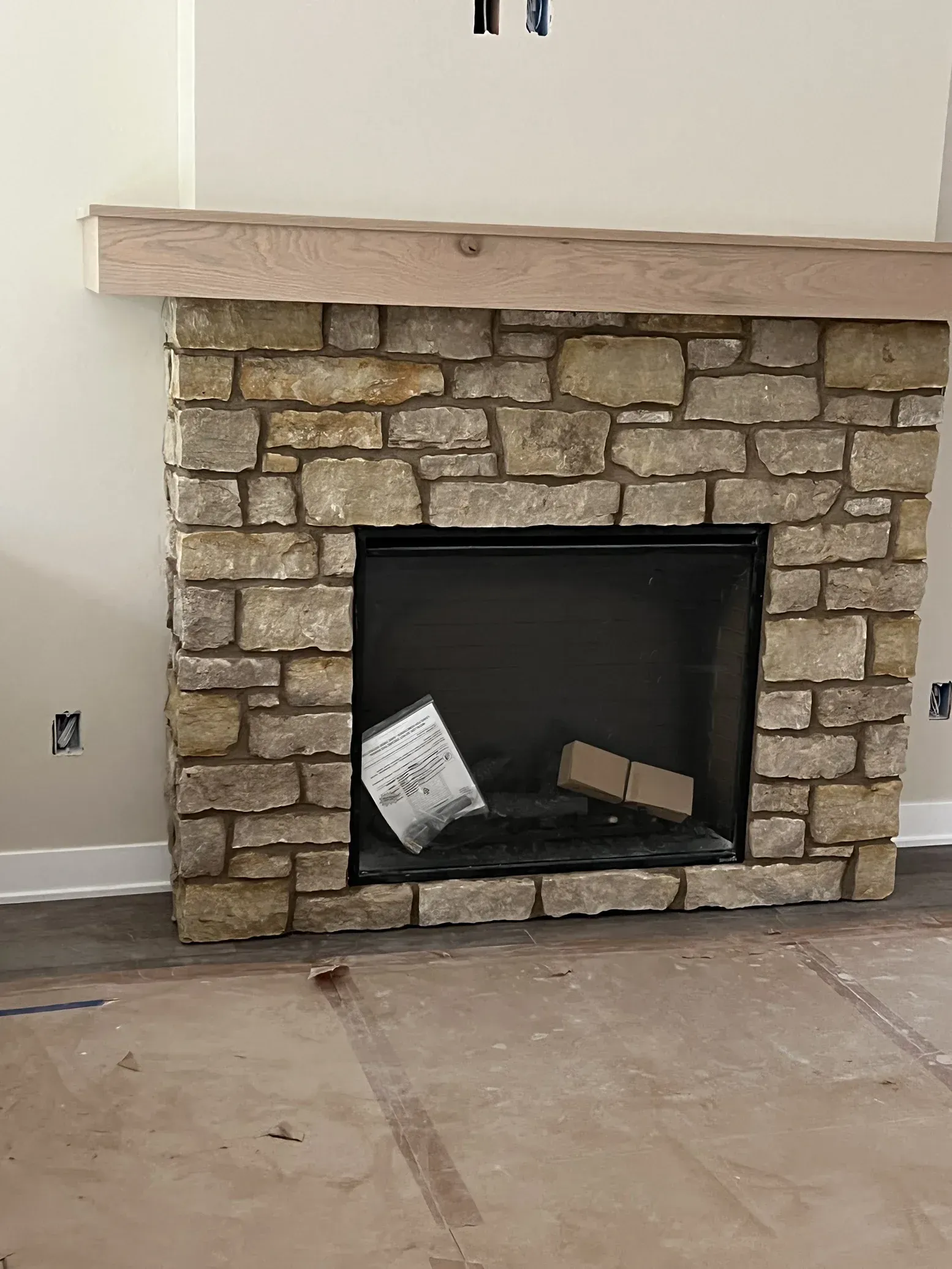 A stone fireplace with a wooden mantle in a living room.