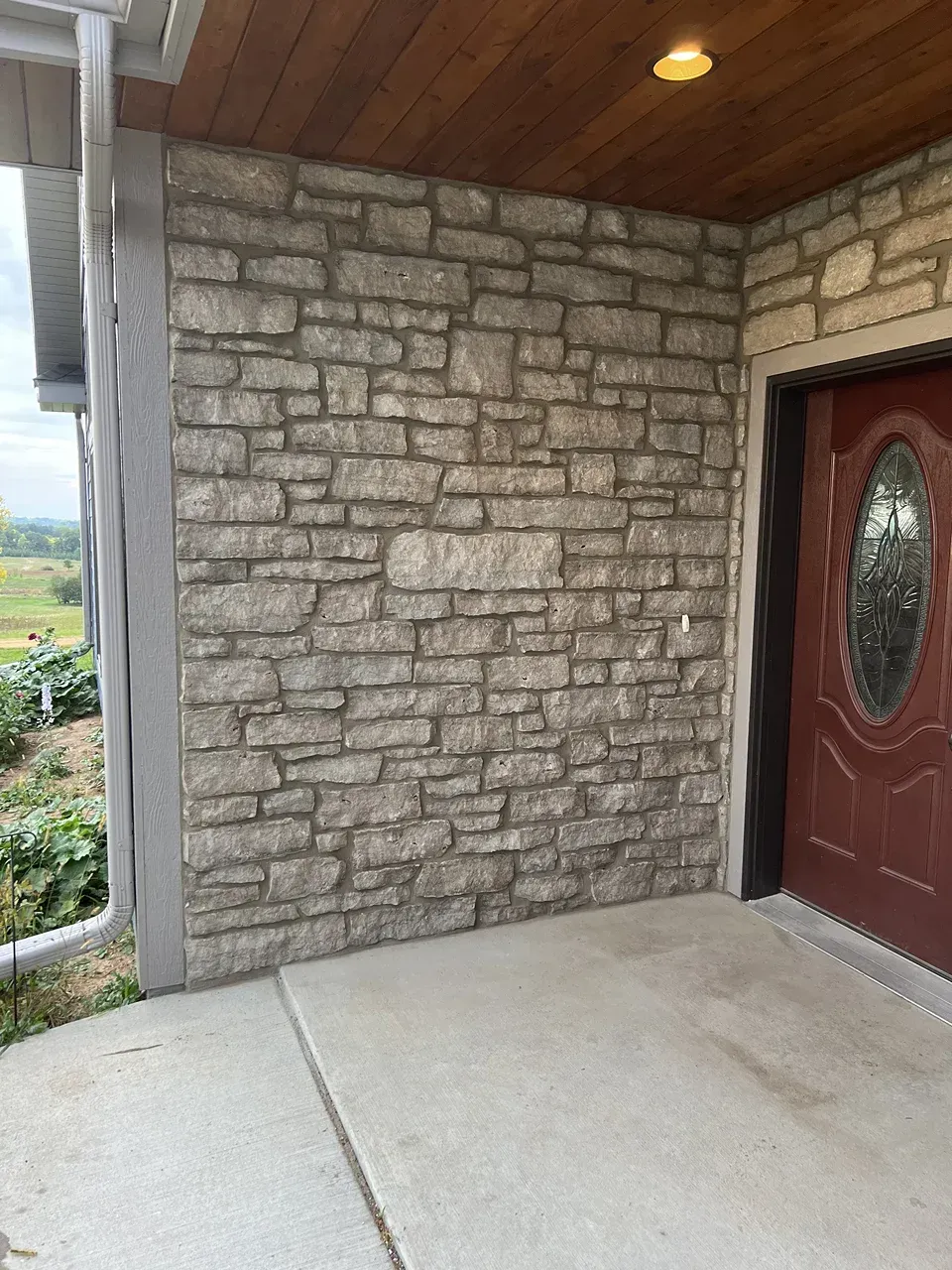 A brick wall with a red door in front of it.