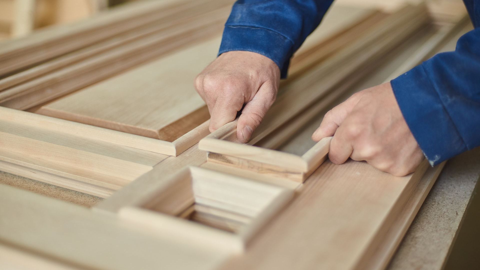 Hands of a carpenter assembling wooden door frame.