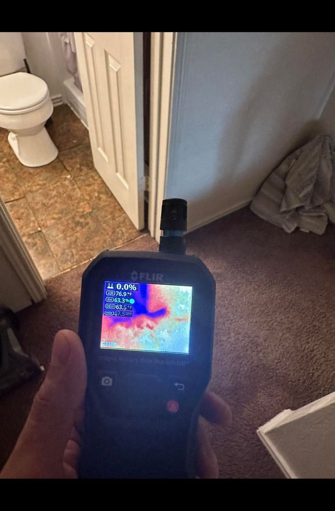 A person is holding a thermal camera in a bathroom.