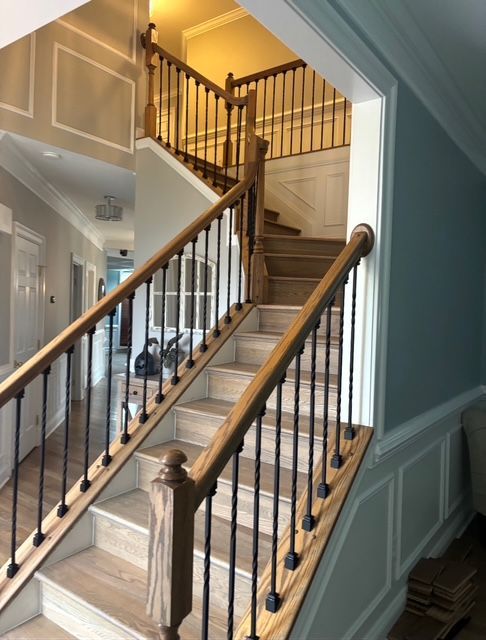 Staircase with wooden handrails and black iron balusters, ascending to a higher level; light wood steps.