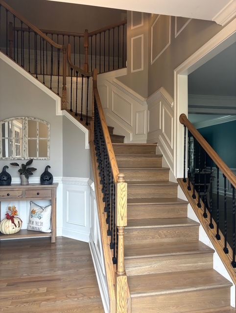 Wooden staircase in a home with white and tan walls and black metal railings.
