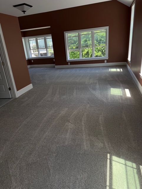 Empty room with gray carpet, brown walls, and multiple windows.