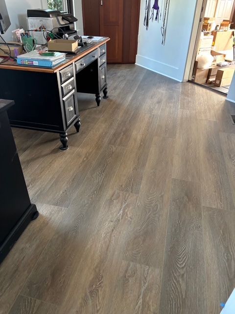 Wooden flooring in a room with a desk, door, and doorway.