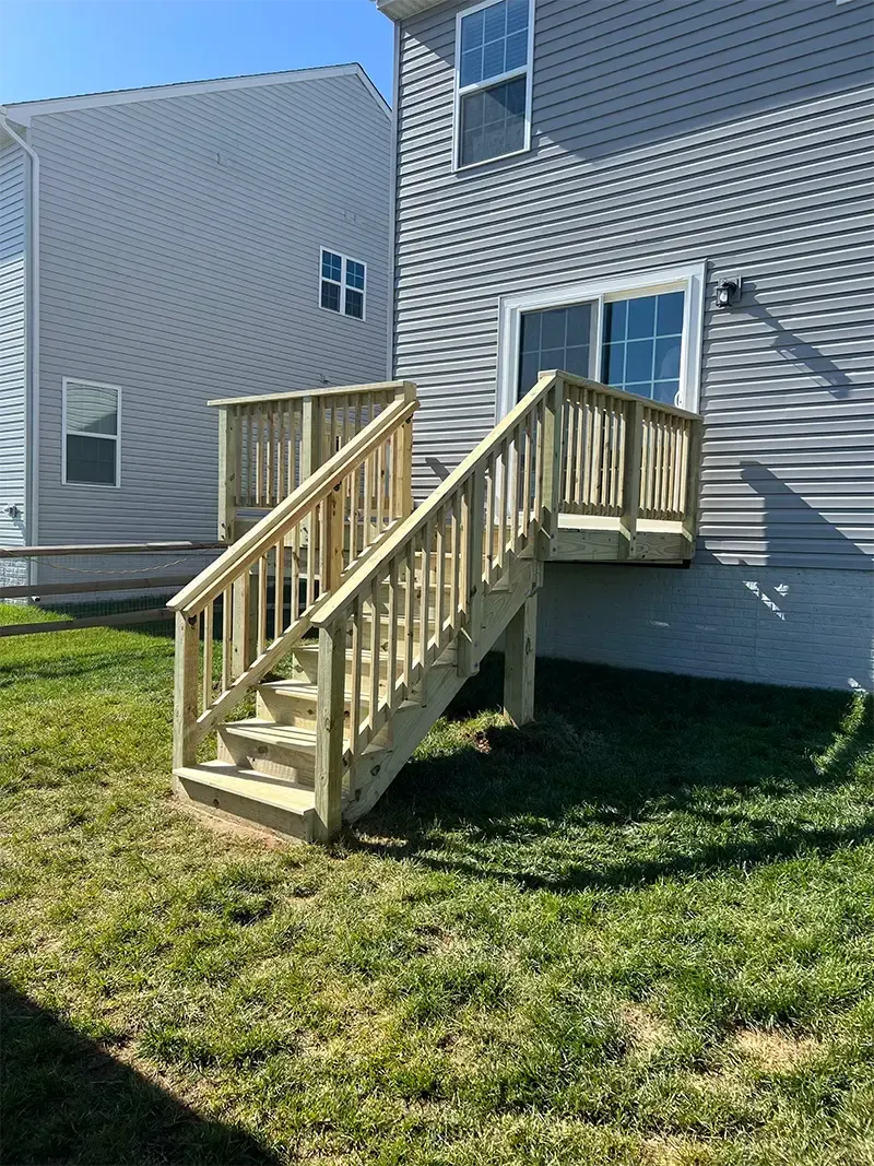 wooden deck and stairs leading to brushed concrete patio
