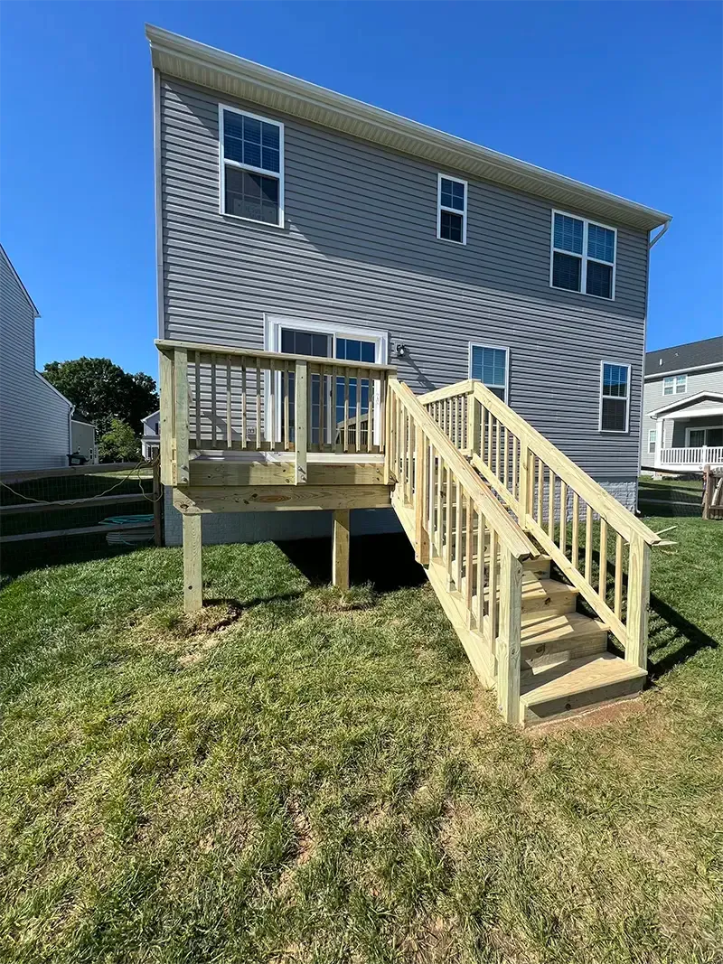 wooden deck and stairs leading to brushed concrete patio
