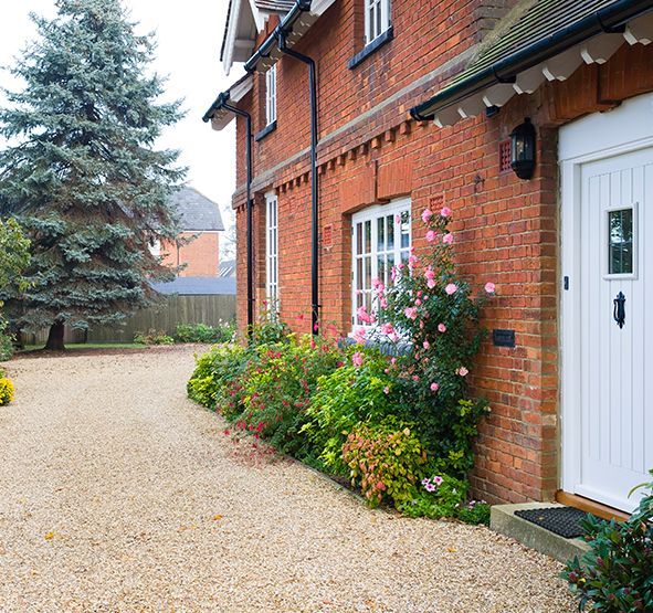 a brick house with a white door and a gravel driveway