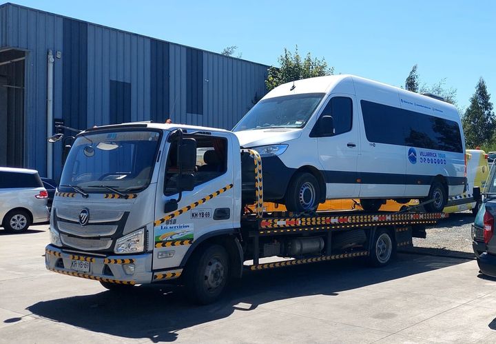 Una grúa está remolcando una camioneta blanca en un estacionamiento.
