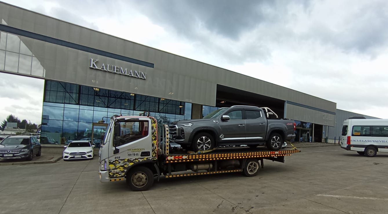 Una grúa transporta una camioneta delante de un edificio.
