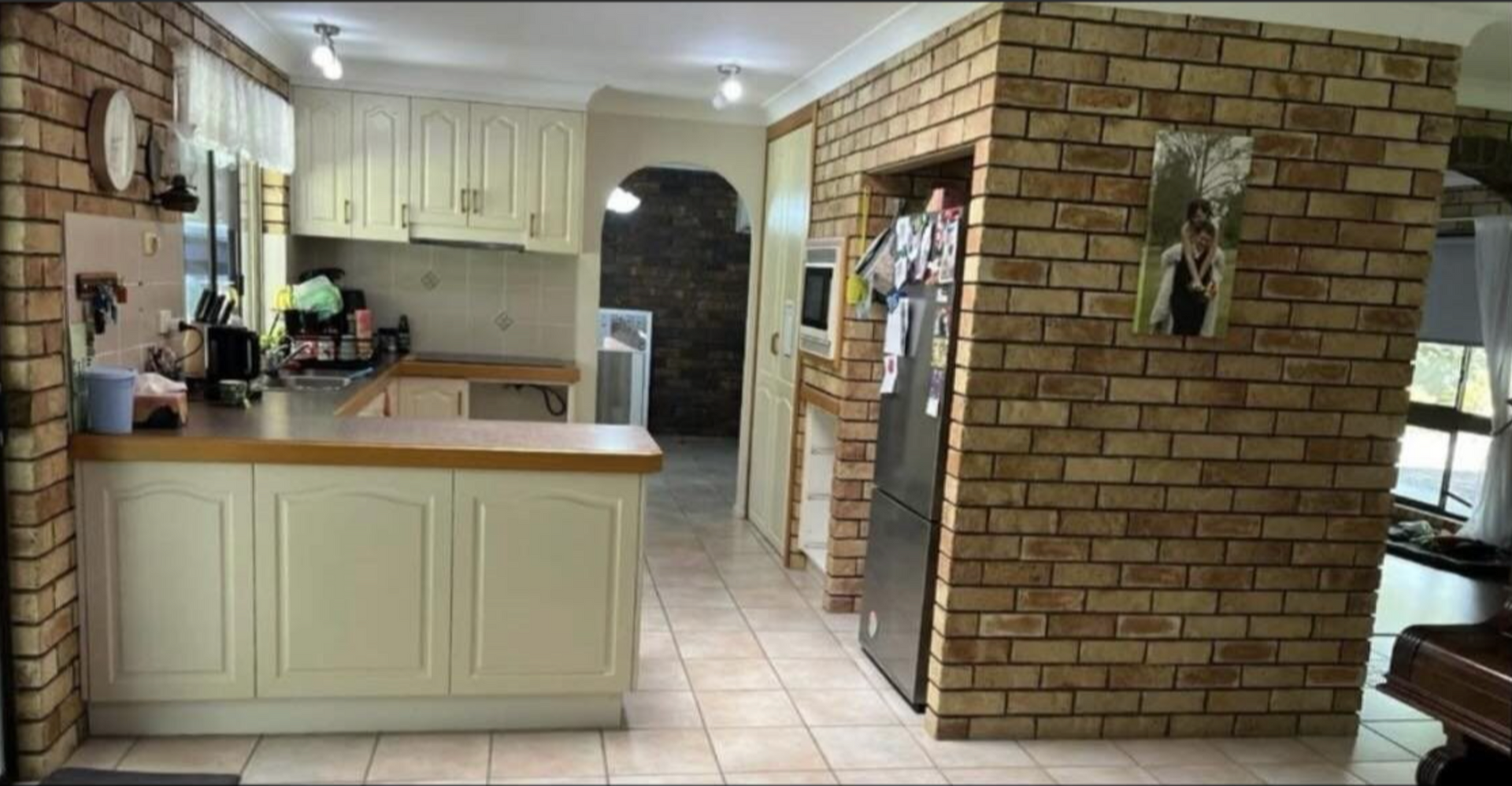 A kitchen with a brick wall and white cabinets.