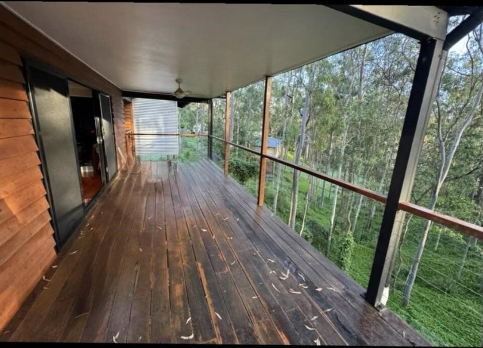 A large wooden deck with a view of a forest.