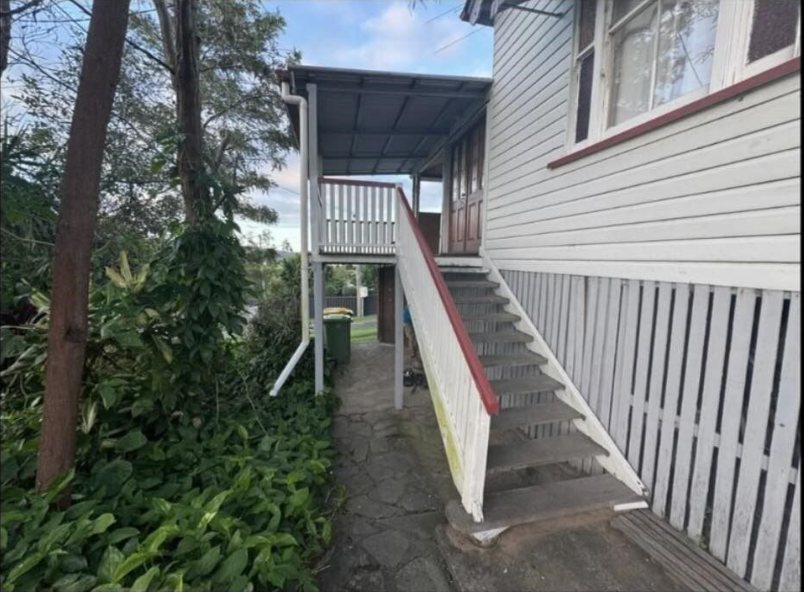 A white house with stairs leading up to the second floor