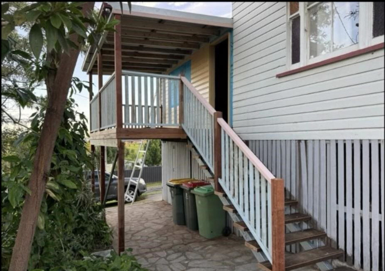 A white house with stairs leading up to a deck