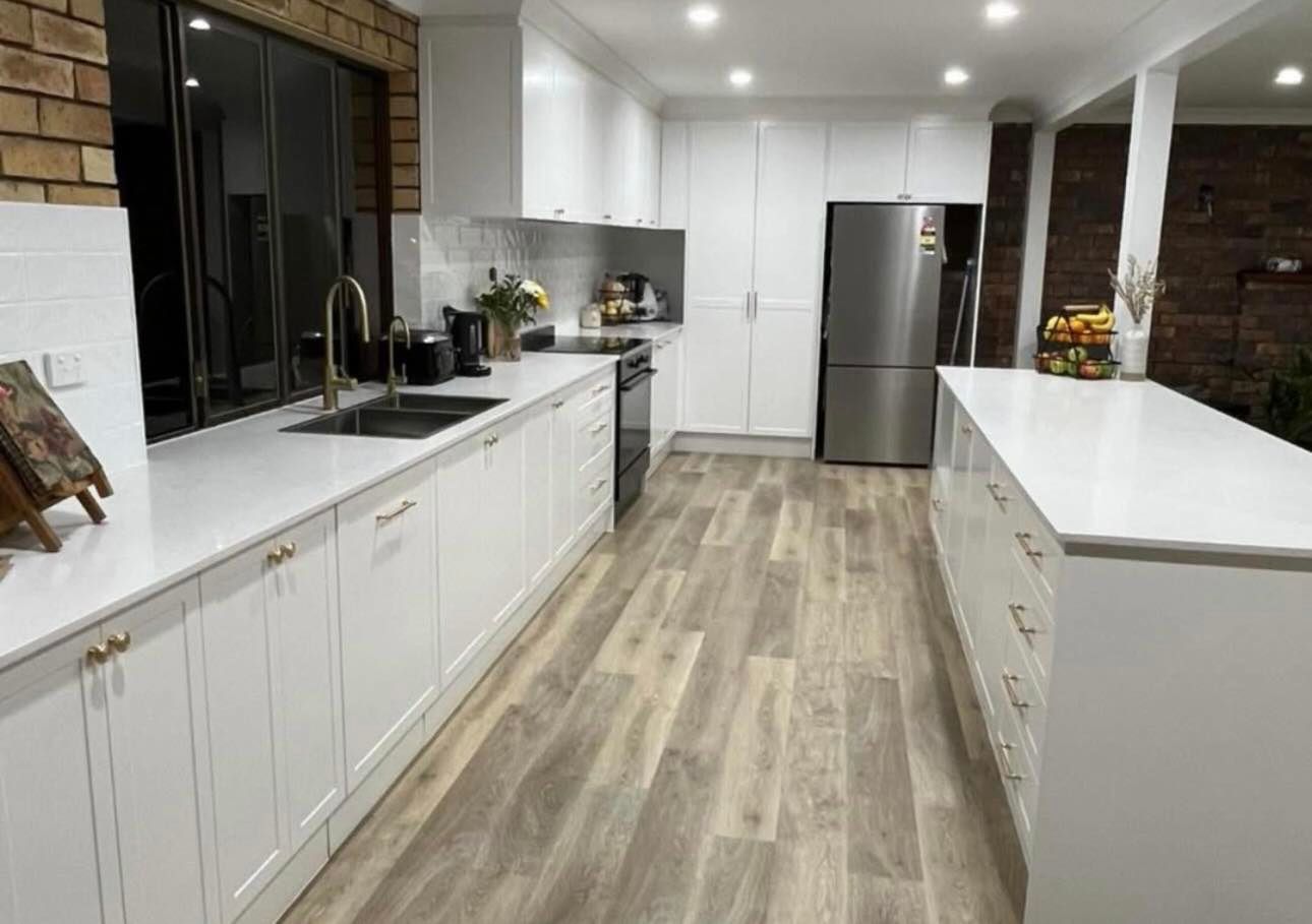 A kitchen with white cabinets , stainless steel appliances , a sink , and a refrigerator.