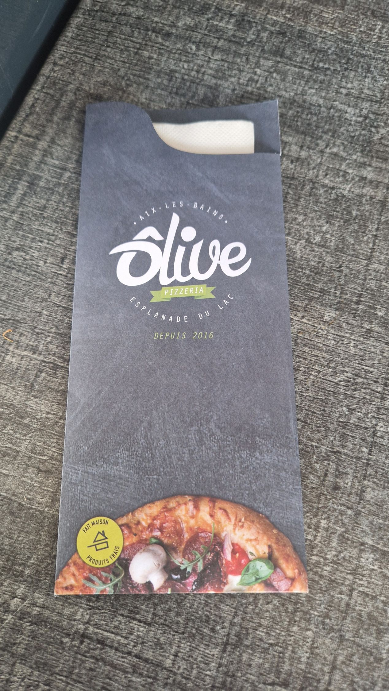 Porte-serviettes avec logo « Slice » et motif pizza. Tissu gris, serviette blanche visible.