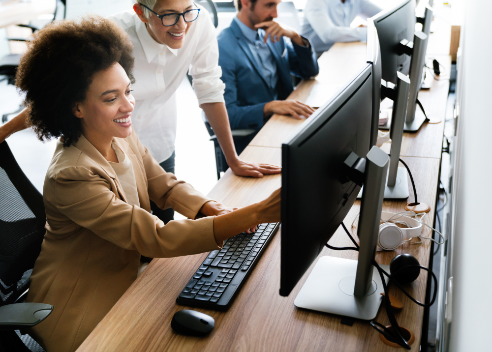 A woman is sitting at a desk looking at a computer screen.