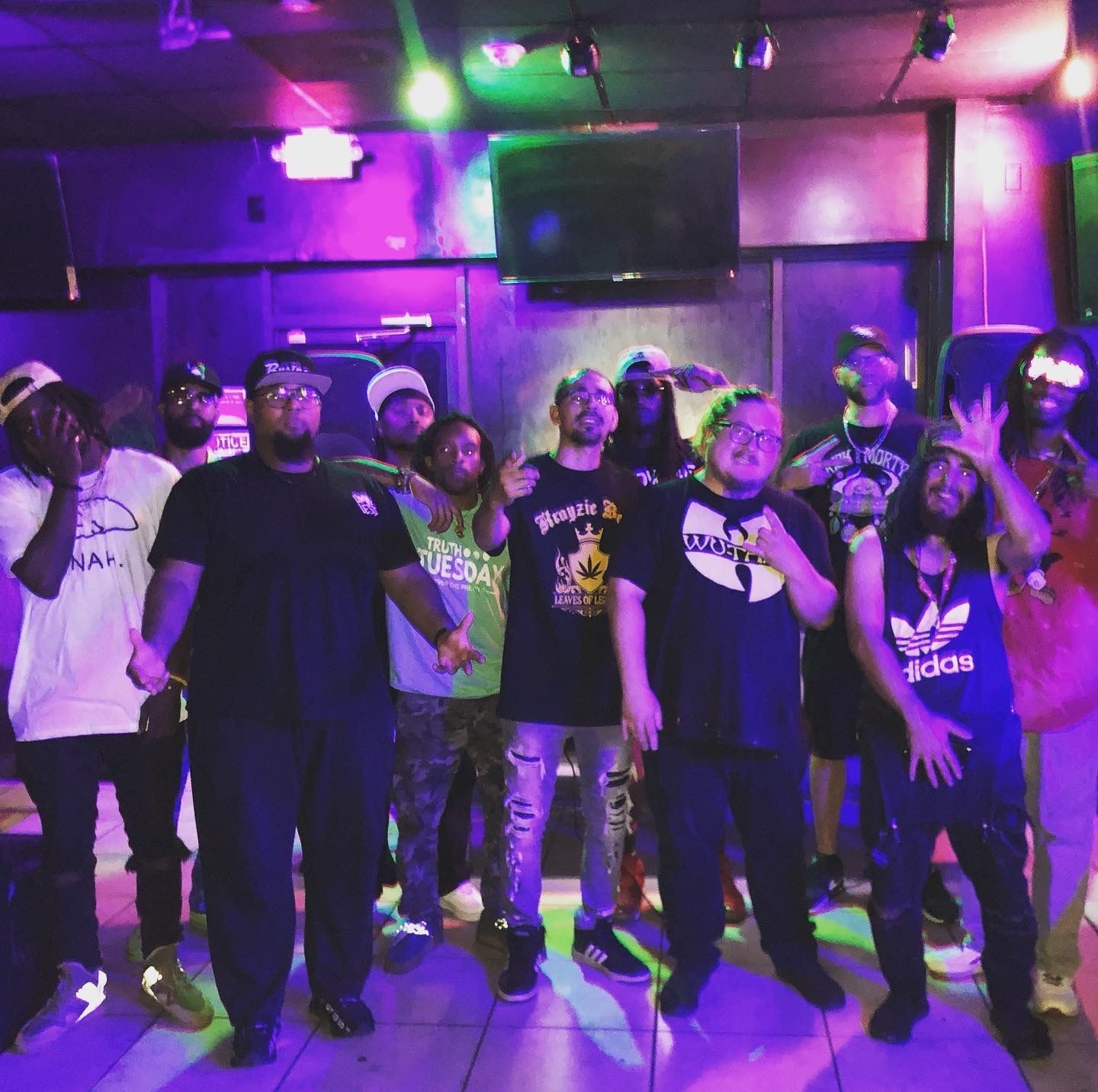 A group of people posing for a picture with one wearing a wu tang shirt