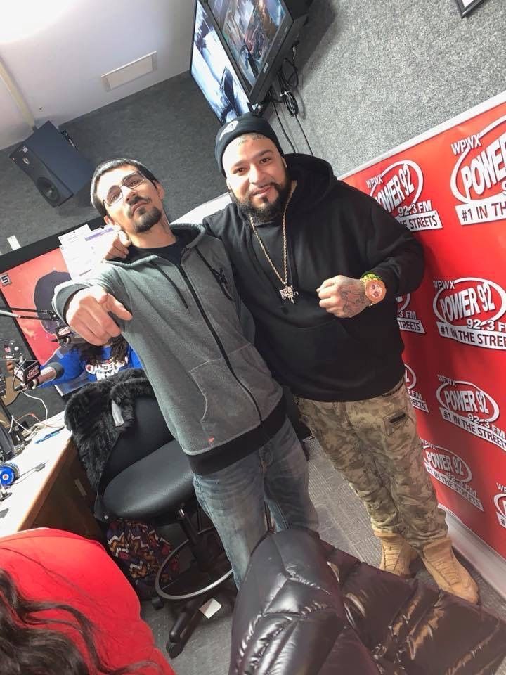 Two men are posing for a picture in front of a wall with the word power on it.