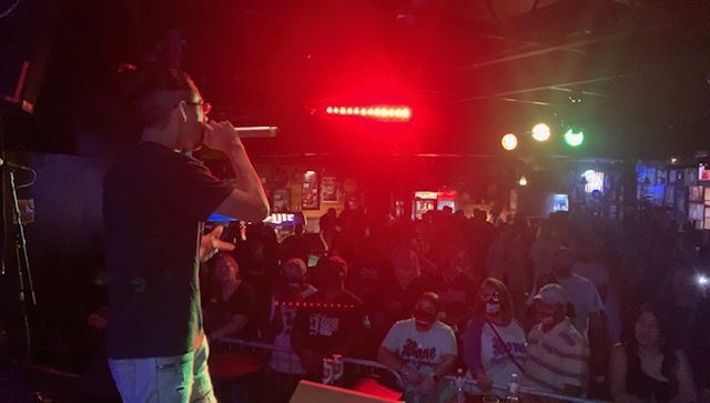 A man is standing on a stage holding a microphone in front of a crowd of people.