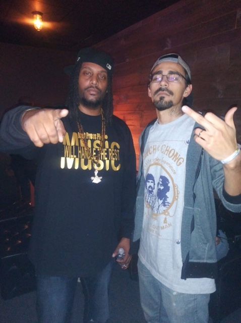 Two men standing next to each other one wearing a shirt that says music