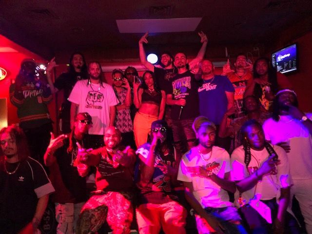 A group of people are posing for a picture in a room with purple lights