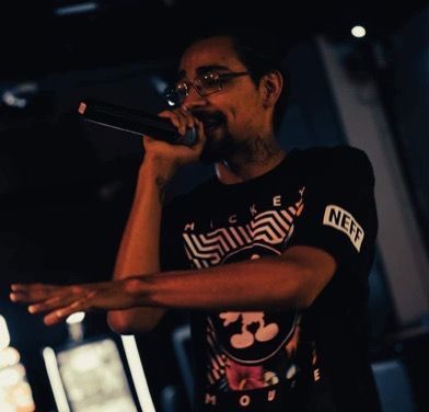 A man singing into a microphone with the word neff on his arm