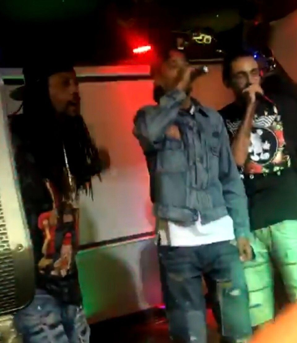 A man with dreadlocks is singing into a microphone