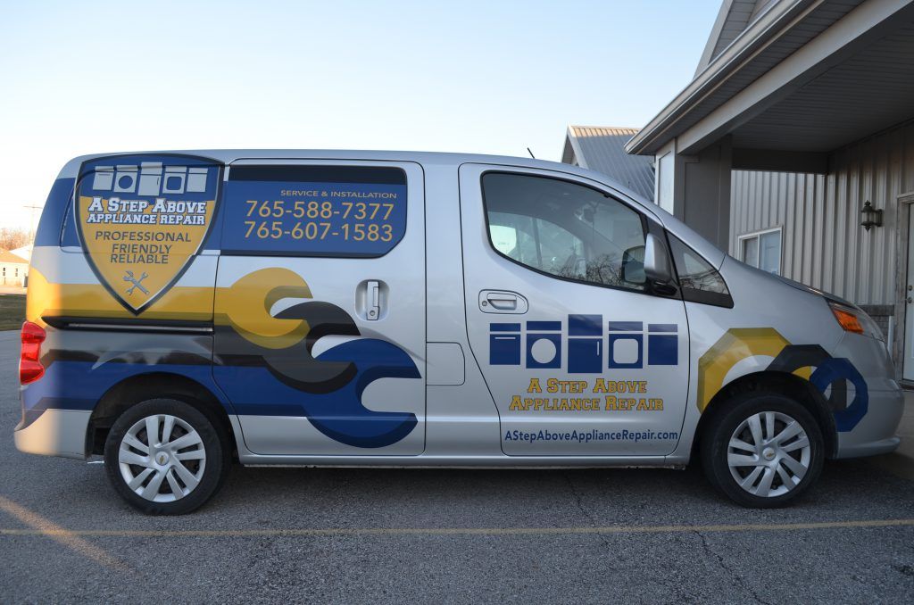A silver van with a wrench on the side is parked in front of a building
