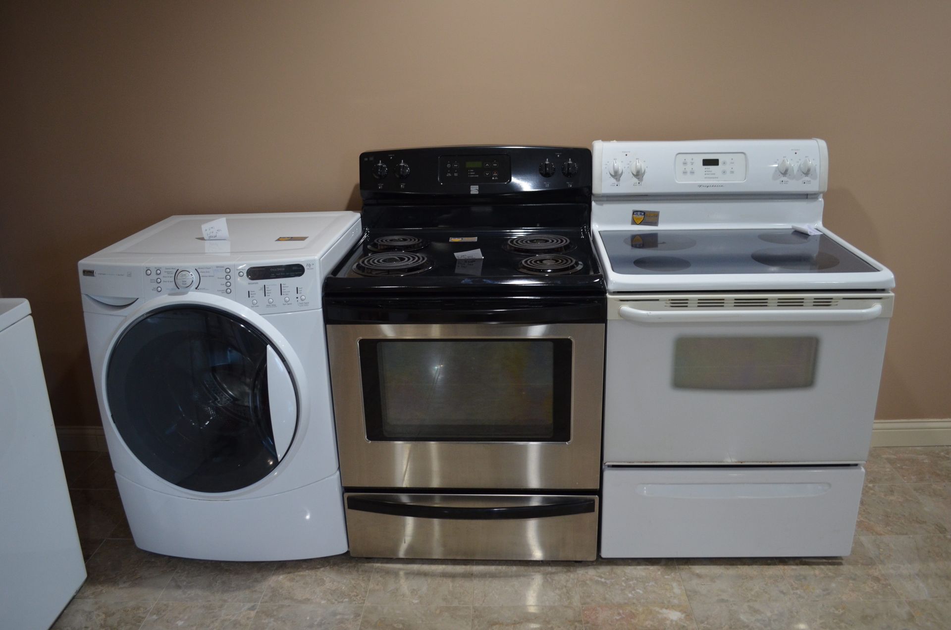 A washer, dryer, stove and microwave are sitting next to each other.
