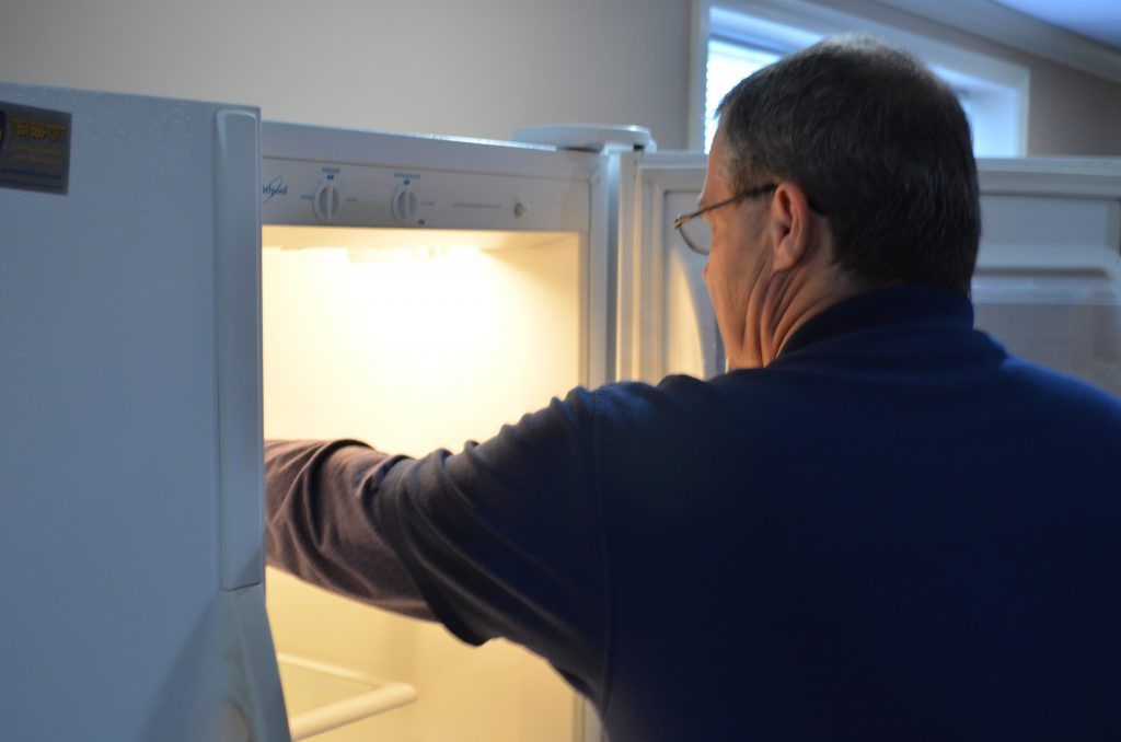 A man in a blue shirt is opening a refrigerator door