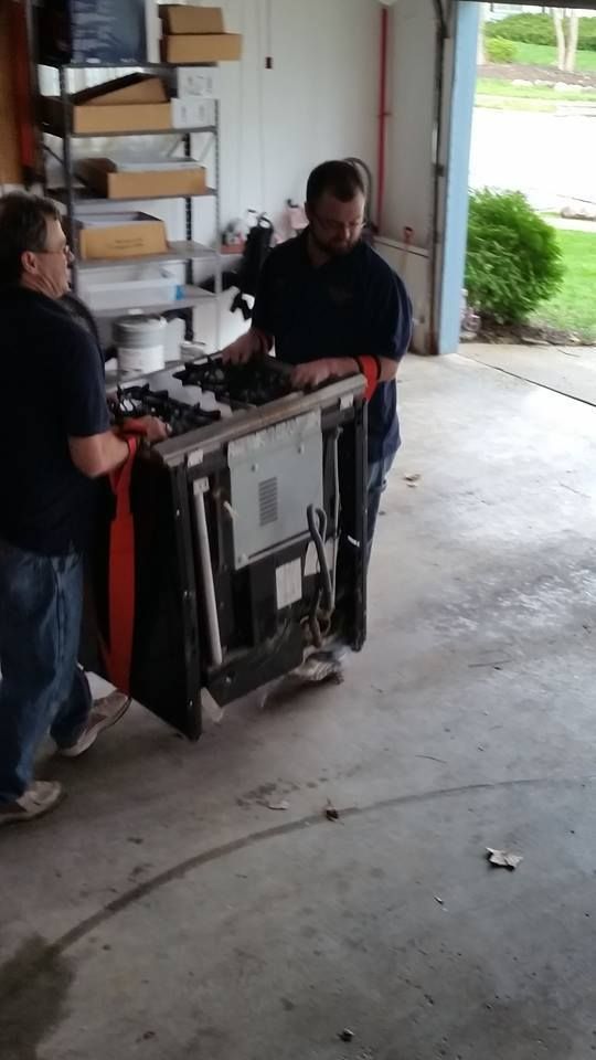 Two men are carrying a large piece of furniture in a garage