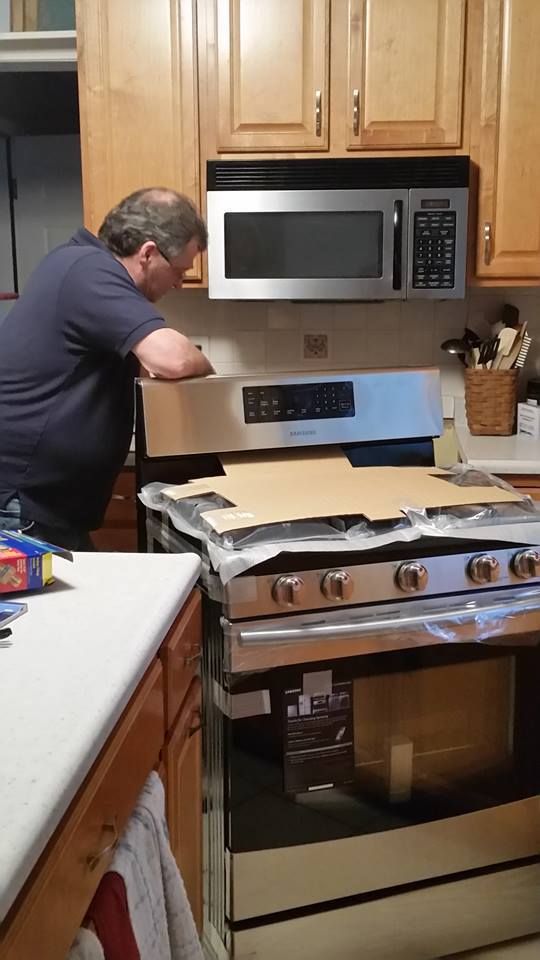 A man is working on a stove in a kitchen