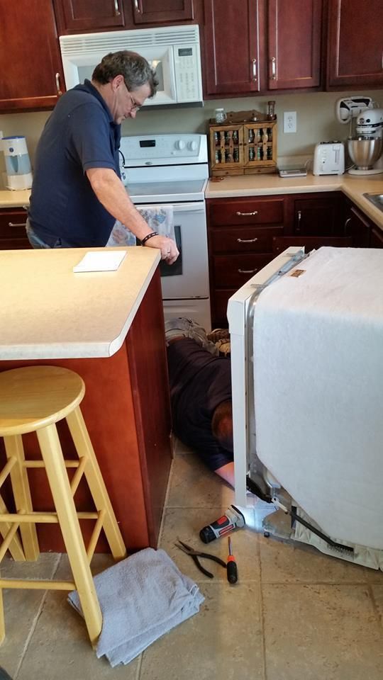 A man is working on a refrigerator in a kitchen