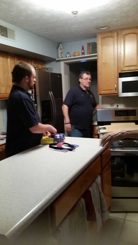 Two men are standing in a kitchen talking to each other