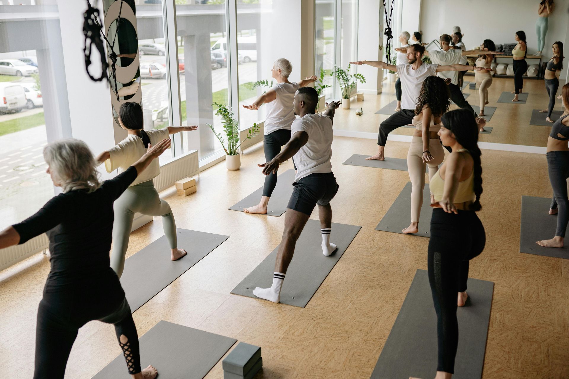 Des personnes participent à un cours de yoga, s'étirant et prenant des poses sur des tapis dans un studio lumineux.