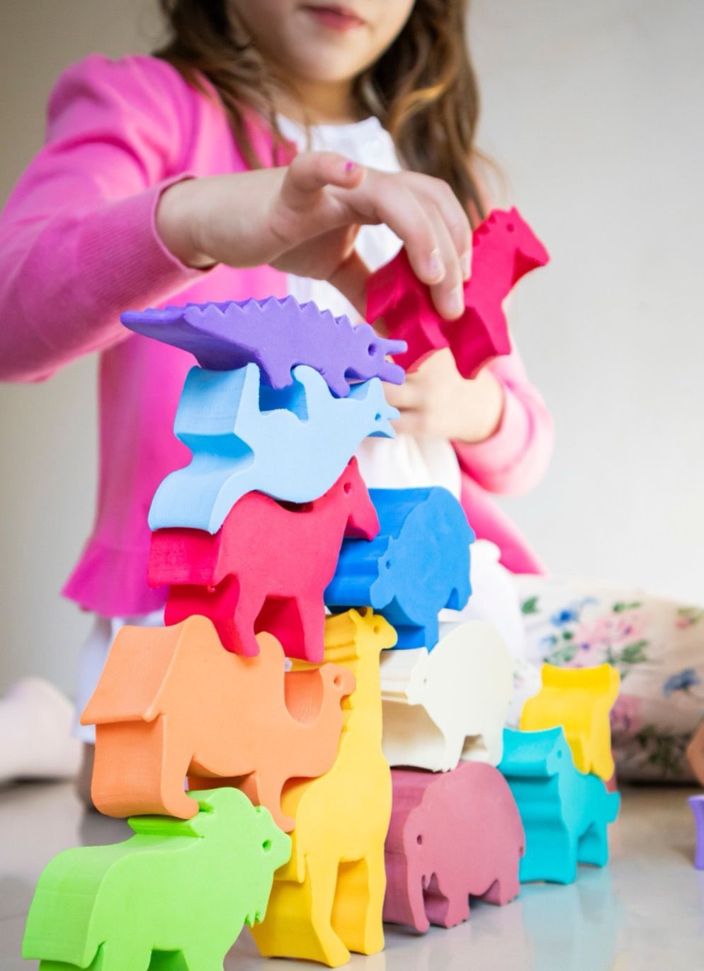 Niño apilando bloques de colores con forma de animales sobre una mesa.