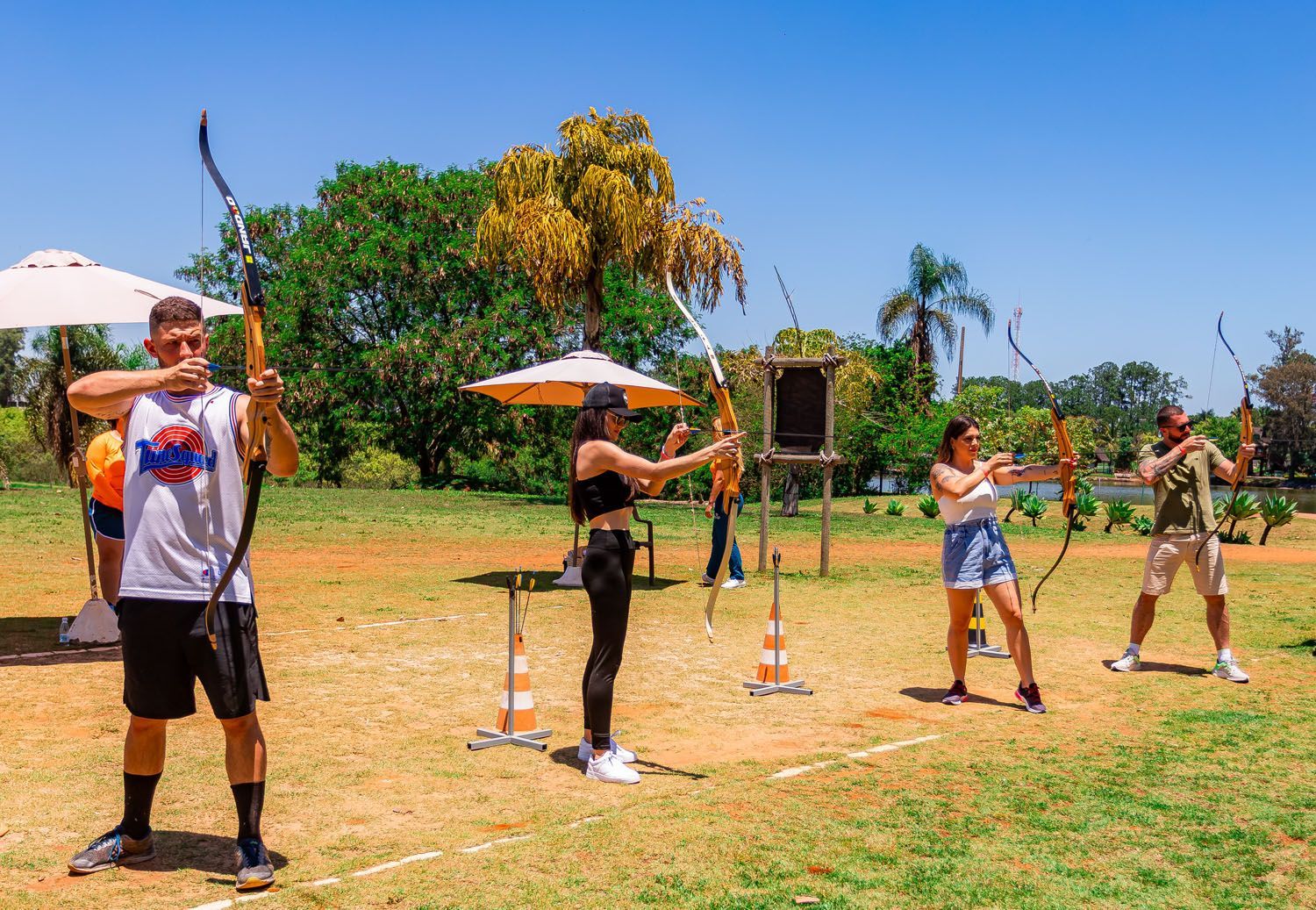 Um grupo de pessoas pratica tiro com arco em um campo.