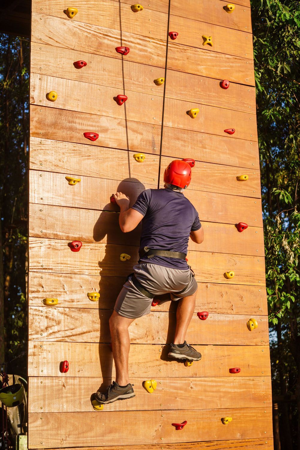 Um homem está escalando uma parede de escalada de madeira.