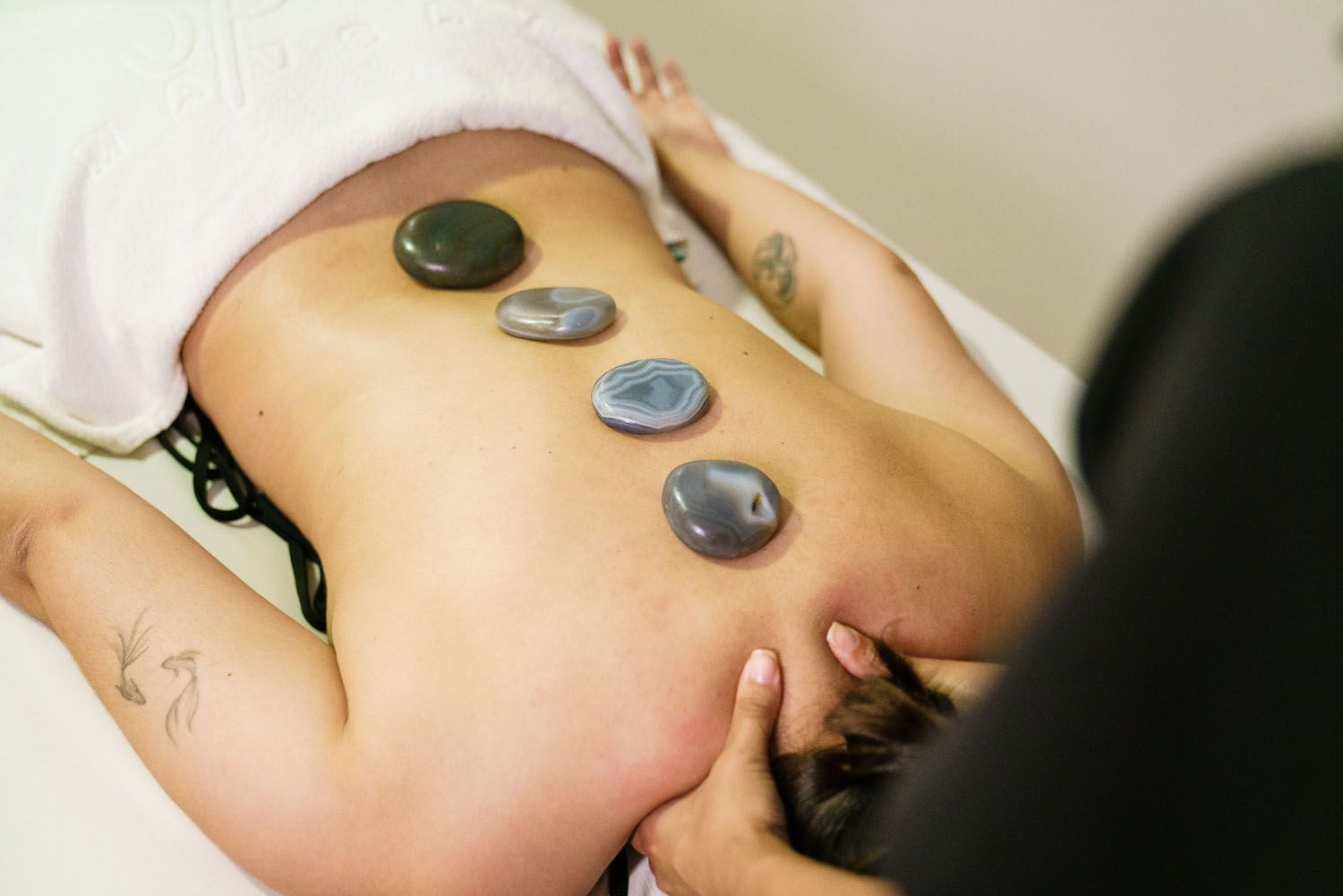 Mulher recebendo uma massagem com pedras quentes nas costas em um spa.