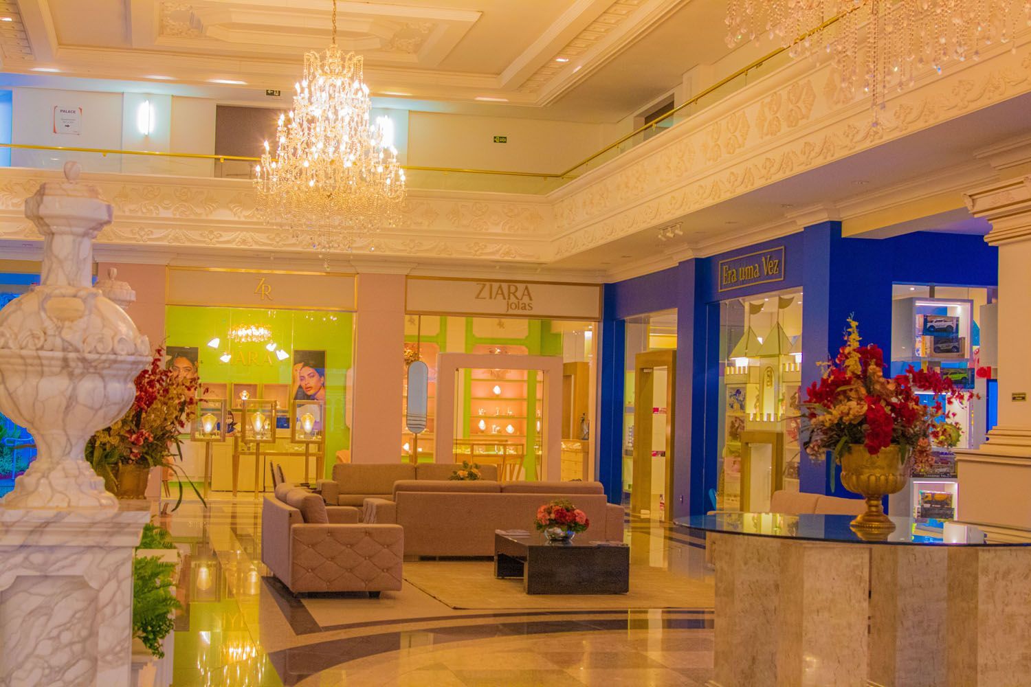 Elegante lobby do hotel com lustre, lojas e assentos.