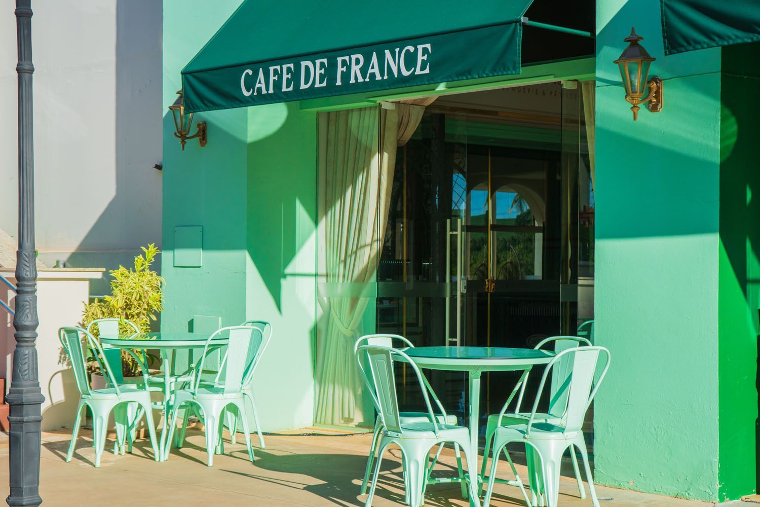 Um café verde com mesas e cadeiras sob um toldo