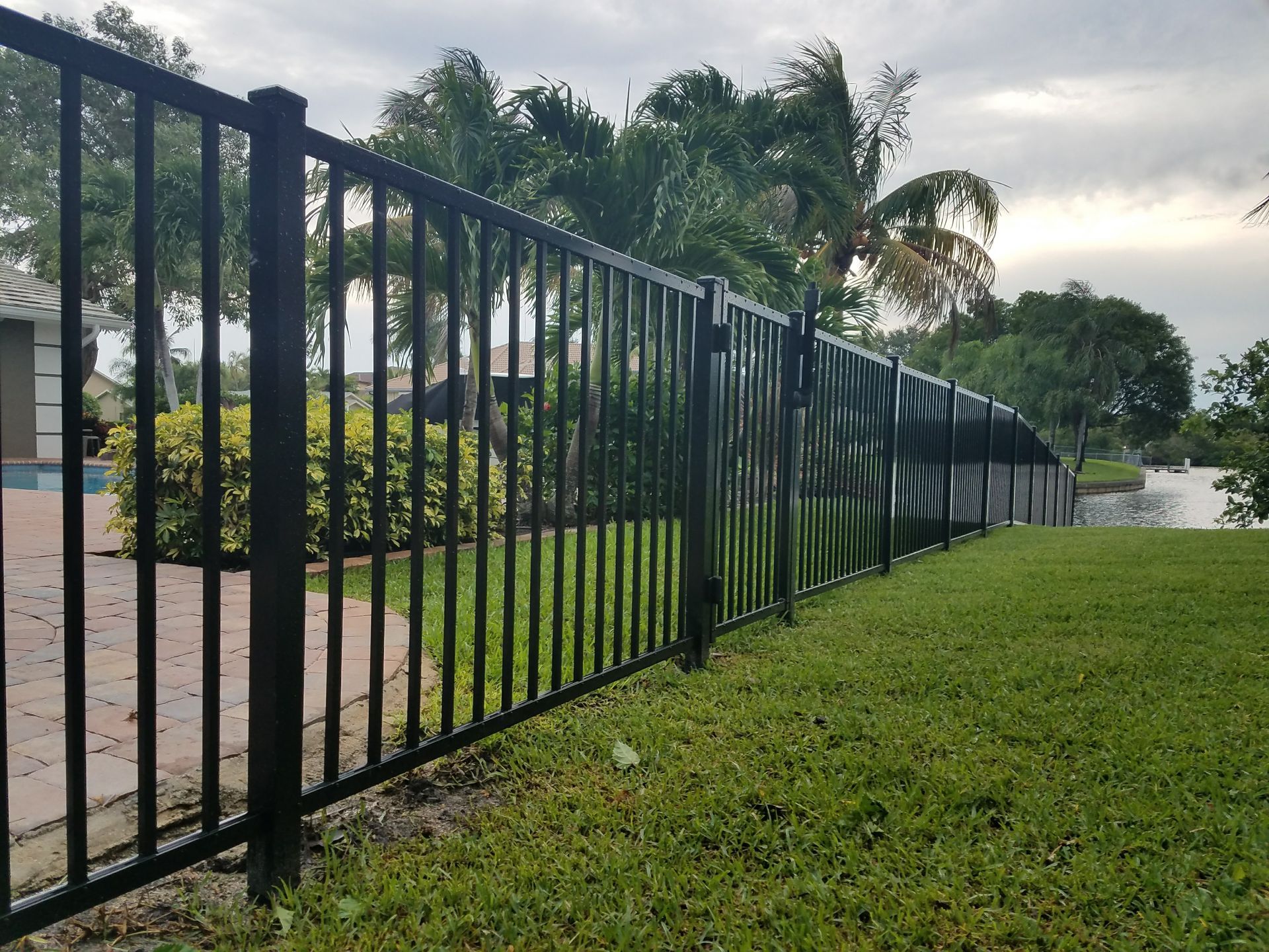A black metal fence surrounds a lush green field.