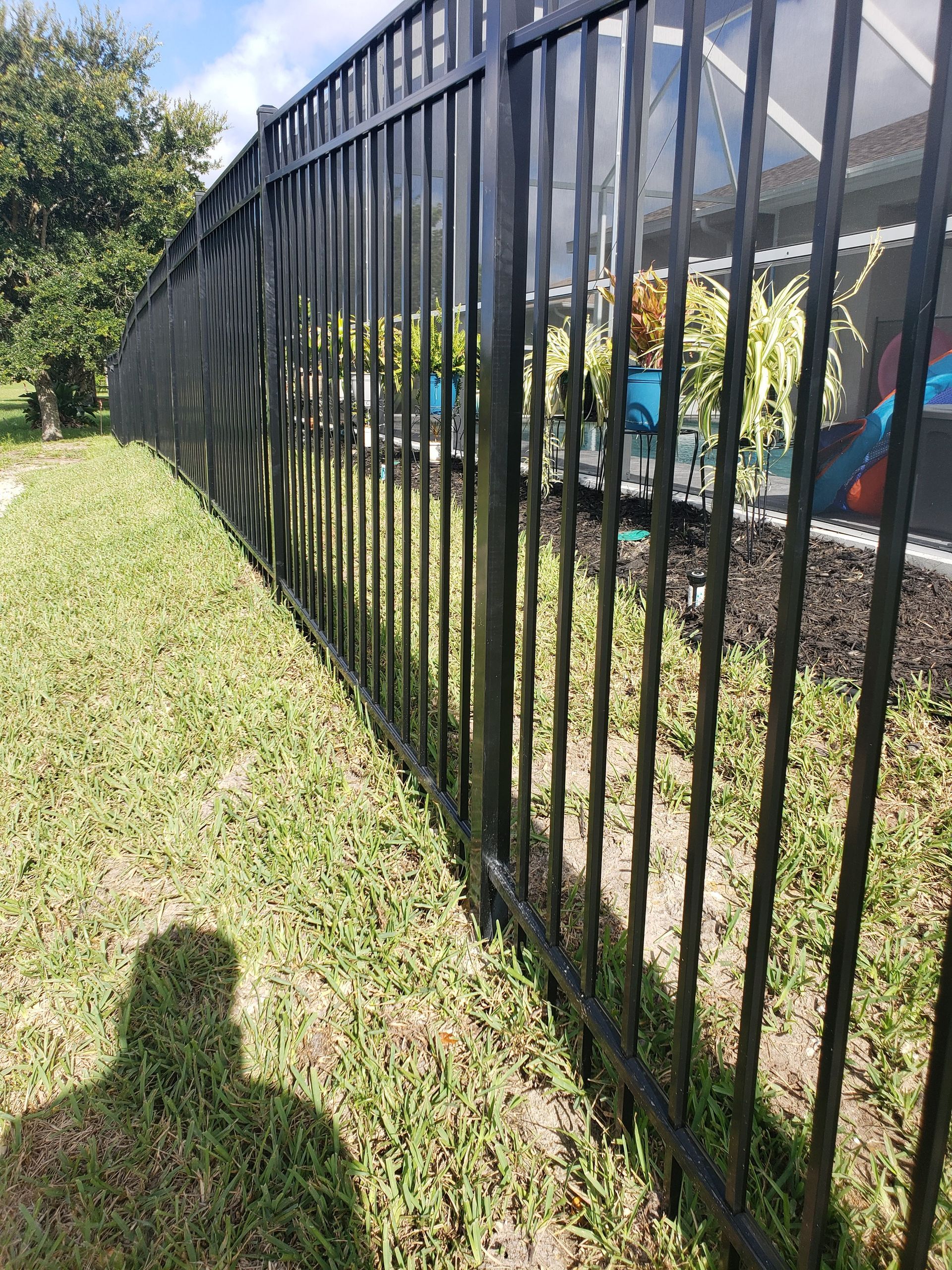 A black metal fence surrounds a lush green yard.