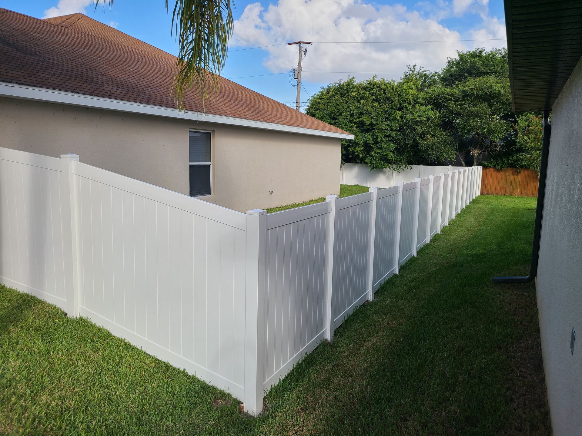A white fence is in the backyard of a house.