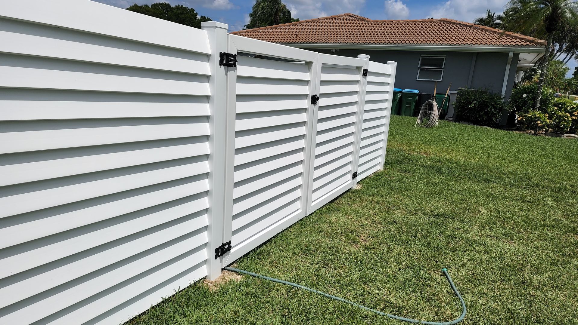 A white fence is sitting in the grass in front of a house.